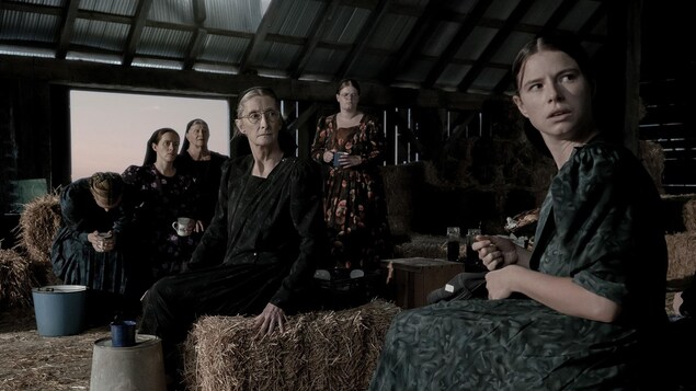 Six femmes installées dans une grange regardent vers la droite, dans une scène du film «Women Talking».