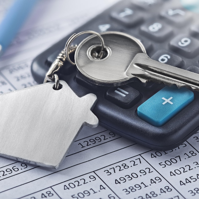Une clé attachée à un porte-clés en forme de maison déposée sur une calculatrice.