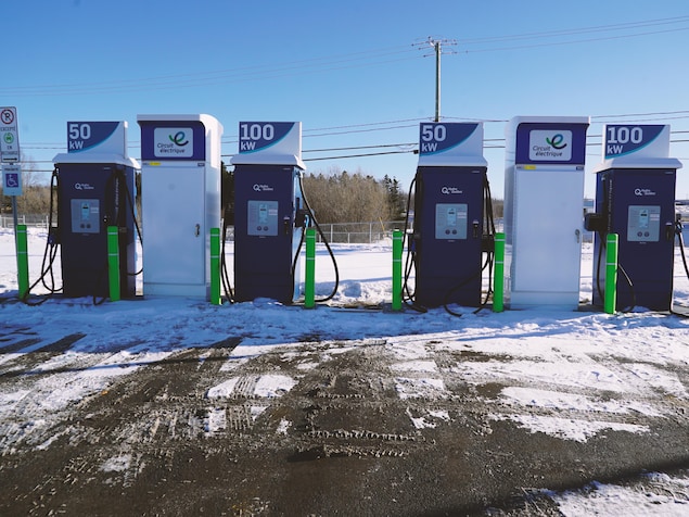 Quatre bornes de recharge de véhicules électriques dans un stationnement en hiver.