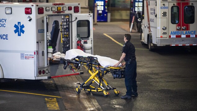 Un ambulancier paramédical tire une civière d'une ambulance. 