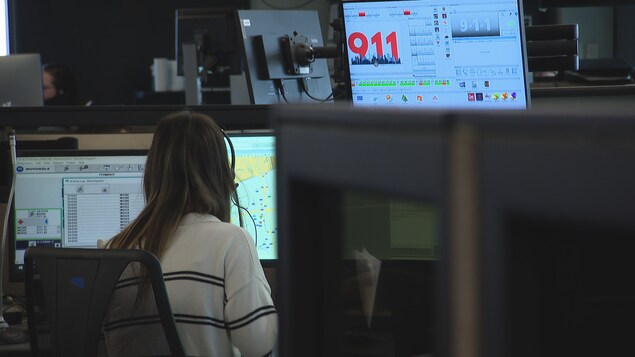Une agente du 911 devant les ordinateurs.