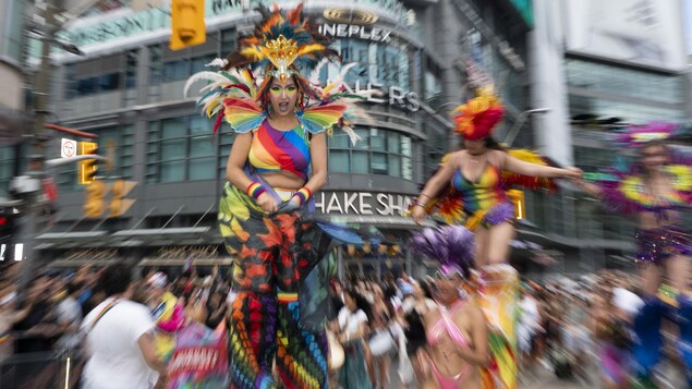 Des femmes en costumes colorés défilent sur des échasses.