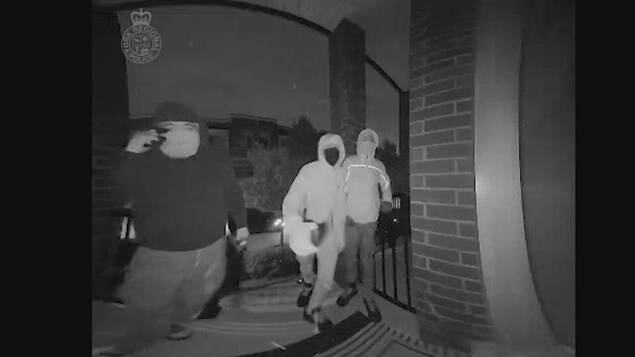 Image extraite d'une vidéo surveillance où l'on voit trois personnes aves des visages dissimulés essayant d'entrer par effraction dans une maison.
