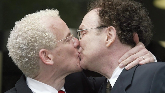 Michael Stark et Michael Leshner s'embrassent, habillés en complet veston-cravate.