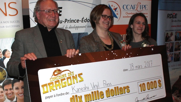 Le premier ministre de l'Î.-P.-É. Wade MacLauchlan aide Nicole Allain, à la droite, coordonnatrice du Concours des dragons, à présenter le chèque de 10 000$ à la championne Ghislaine Cormier de Charlottetown, de Kaneshii Vinyl Press. Le premier ministre de l'Î.-P.-É. Wade MacLauchlan aide Nicole Allain, à la droite, coordonnatrice du Concours des dragons, à présenter le chèque de 10 000$ à la championne Ghislaine Cormier de Charlottetown, de Kaneshii Vinyl Press.