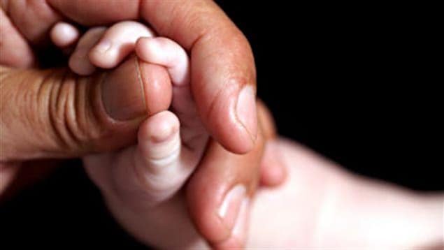 Une main d'adulte qui tient une main de bébé.