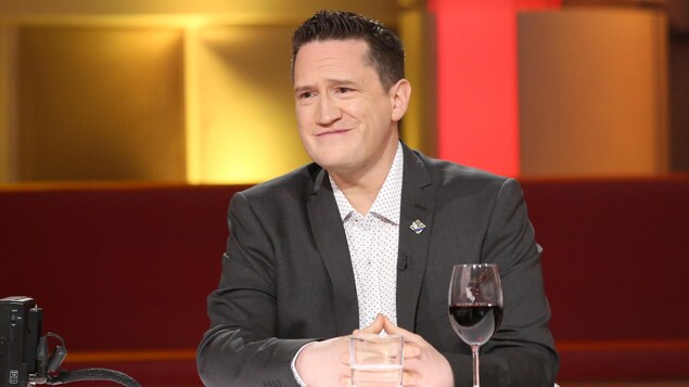 Benoit Charette porte une chemise à pois et un veston gris foncé.