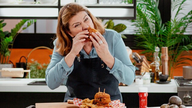 Marina Orsini prend une bouchée du burger frit.