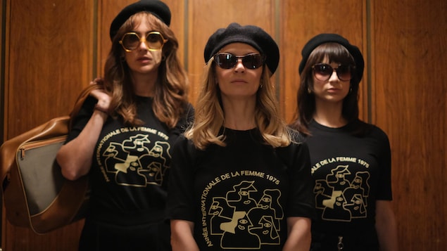 Micheline, Huguette et Marie-Josée portent un t-shirt de l'Année internationale de la femme 1975, des lunettes de soleil et un béret noir.