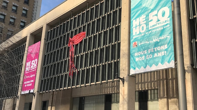 Une ceinture fléchée rouge géante est nouée sur la façade de l'hôtel de ville de Winnipeg.