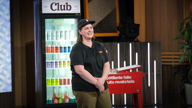 Elle est debout devant un réfrigérateur contenant des produits Club.