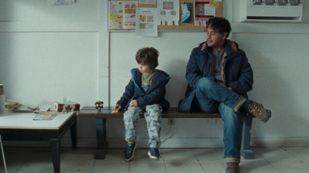 Un petit garçon et un homme assis côte à côte dans une salle d'attente.