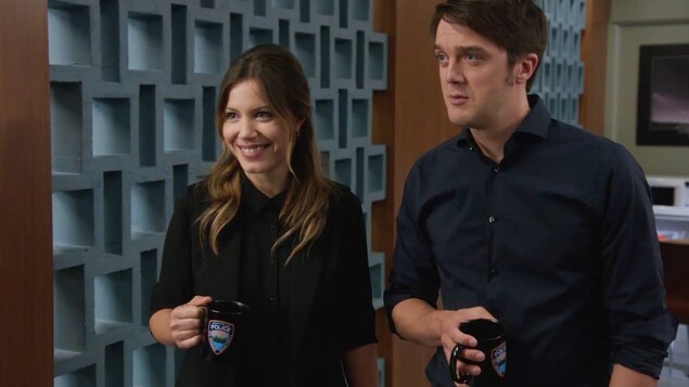 Nadine et Patrick regarde droit devant eux en souriant avec une tasse de café dans les mains.