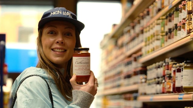 Catherine St-Laurent dans une épicerie fine, tenant un pot de confiture qui porte son prénom. 
