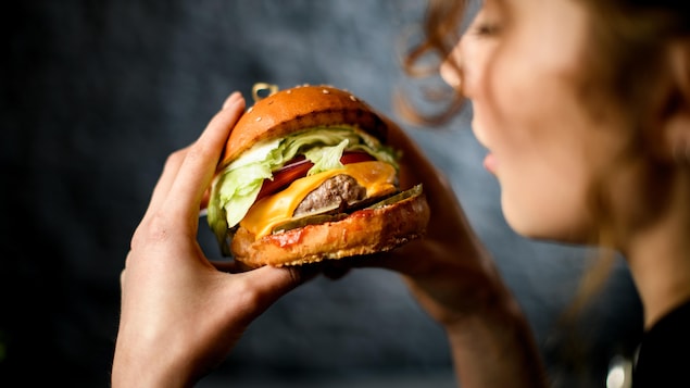 Une personne regarde un hamburger.