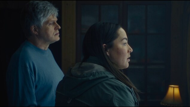 Un homme (Réal Bossé) et une femme (Eve Ringuette) côte à côte regardent par une fenêtre.
