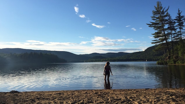 Une femme se baigne dans un lac entouré de nature et d'une plage de sable. Une femme se baigne dans un lac entouré de nature et d'une plage de sable.