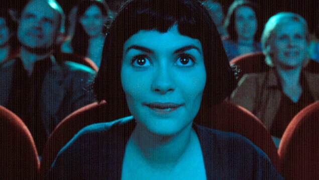 Une jeune fille (Audrey Tautou) fascinée, regarde devant elle, dans une salle de cinéma.