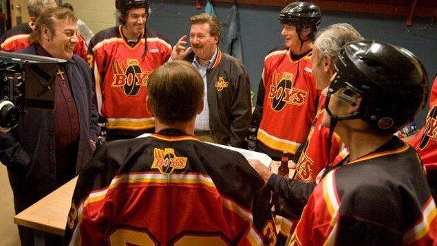 Un groupe d'hommes (dont Pierre Lebeau, Rémy Girard et Marc Messier) portant un chandail ou un blouson avec le logo et le terme Les Boys.