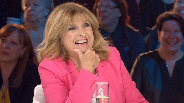 Dominique Michel riant lors d'une entrevue sur un plateau de télé.