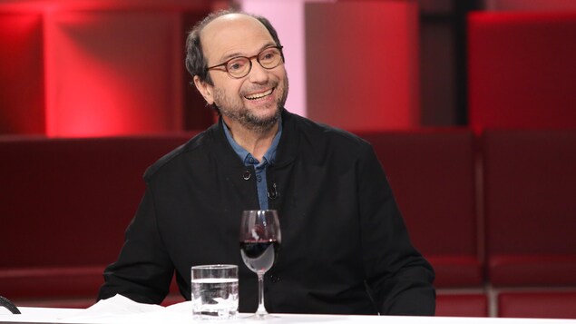Michel Rivard porte une chemise et un blouson bleus.