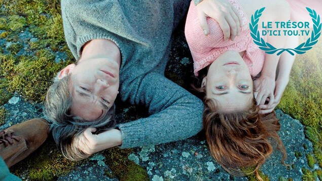 Un jeune homme et une jeune femme allongés dans l'herbe, vus d'en haut.