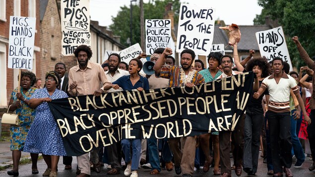 Une foule d'hommes et de femmes noirs manifestent en tenant des pancartes.