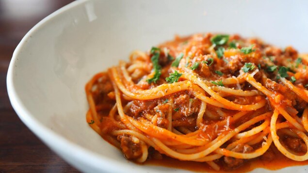 Une assiette blanche contenant des spaghettis bolognaise.