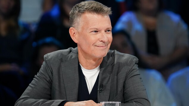 L'homme est assis en studio et sourit.