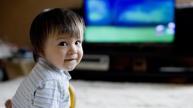 Un jeune garçon regarde la télé dans son salon.