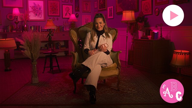 Chloée Deblois est assise dans une chaise dans une chambre décorée de cadres. Le logo de la série L'ABC Intimité et le bouton Jouer sont à droite.