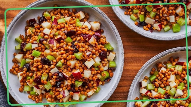 Une salade de lentilles à l’érable et aux pommes dans saladier posé sur une table.
