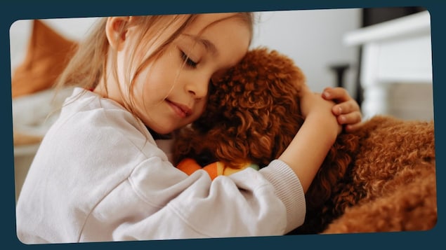 Une petite fille fait un câlin à son chien. 