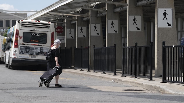 Une femme âgée marche près d'une gare d'autobus.