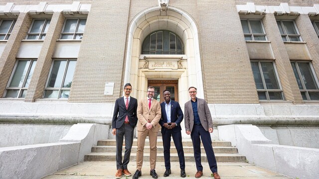 Sameer Zuberi, Steven Guilbault, Allen Alexandre et Luc Rabouin posent devant un édifice patrimonial de Montréal.