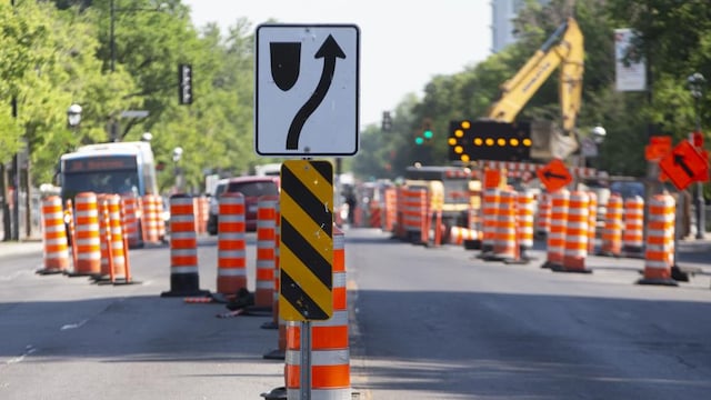 Des cônes orange et des pancartes de signalisation de travaux de construction font dévier la circulation dans une rue.
