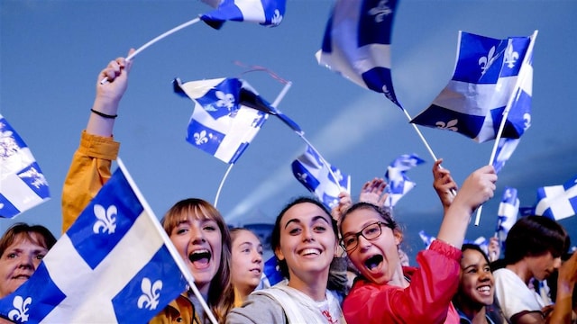 Une foule brandit des drapeaux québécois.