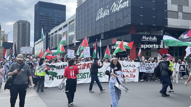 Les manifestants marchent dans la rue derrière une grande banderole qui porte la mention, en anglais : « 76 ans d'occupation, 76 ans de résistance ».
