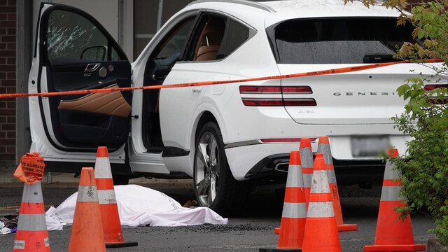 Un corps couvert d'un linceul à côté d'une voiture.