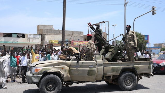 Au Soudan, un véhicule militaire avec des soldats armés qui sont salués par des citoyens. 