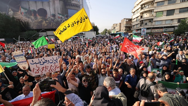 Des Iraniens brandissent des drapeaux et des pancartes lors d'une manifestation.
