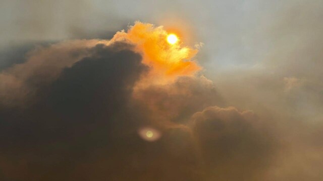 Thick smoke rises towards the skies, veiling the sun.