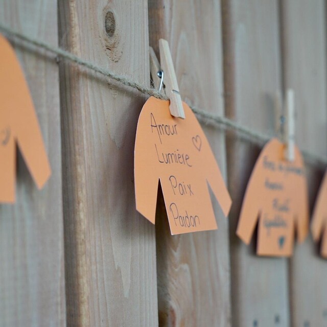 Messages écrits sur de petits chandails orange sur une corde à linge.