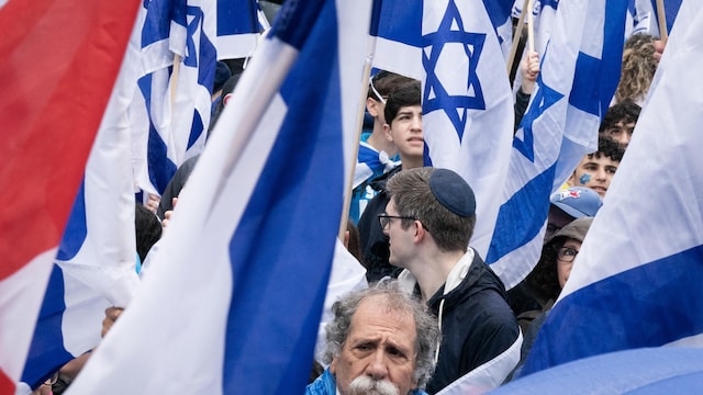Des manifestants visibles entre les drapeaux israéliens.