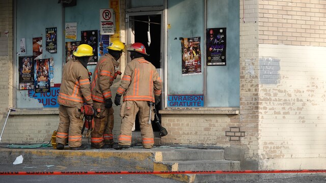 Trois pompiers observent à travers la porte d'un bâtiment.