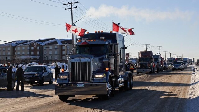 Une file de camions sur la transcanadienne, l'un d'eux arborant des drapeaux canadiens.