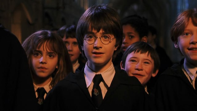 Emma Watson, Daniel Radcliffe et Rupert Grint, qui incarnent respectivement Hermione Granger, Harry Potter et Ron Weasley, sont dans leurs robes de sorciers. Ils se trouvent parmi d'autres nouveaux élèves de l'école de sorcellerie de Poudlard.
