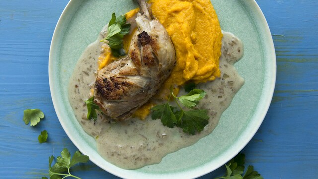 Un poulet braisé au brandy sur un lit de purée de carottes à la moutarde.