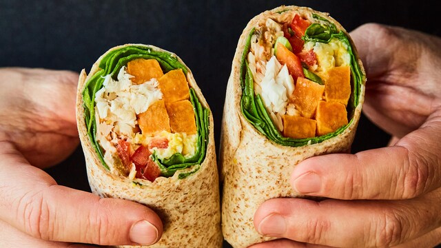 Un homme tient un burrito coupé en deux dans ses mains.