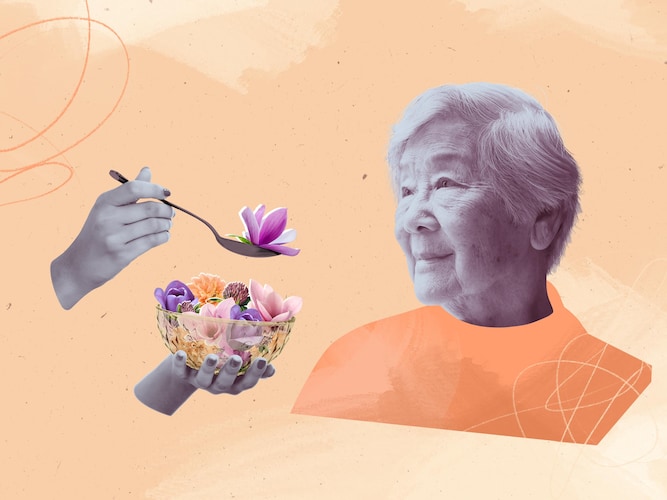Un préposé aux bénéficiaires nourrit une vieille dame avec des fleurs.